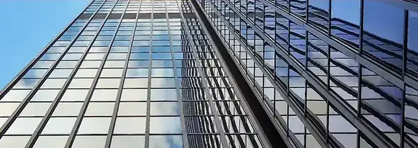 Rascacielos con fachada de cristal reflejando el cielo, simbolizando la modernización y la innovación en el ámbito empresarial.